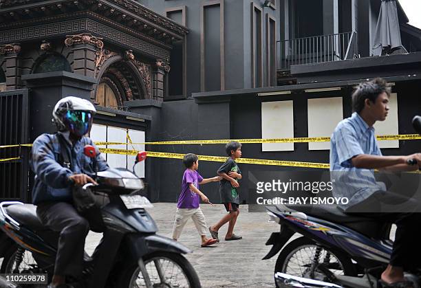 People move past police tape securing the residence of Indonesian rock musician Ahmad Dhani, who is known for his songs protesting against religious...