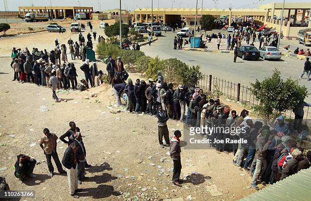Refugees from Chad stand in a line to receive food as they continue to be stranded at the Libyan/Egyptian border crossing after leaving Libya about...