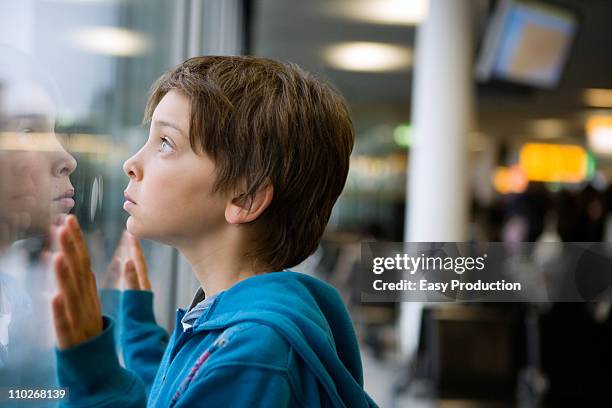 young boy looking through a window - bali airport ストックフォトと画像