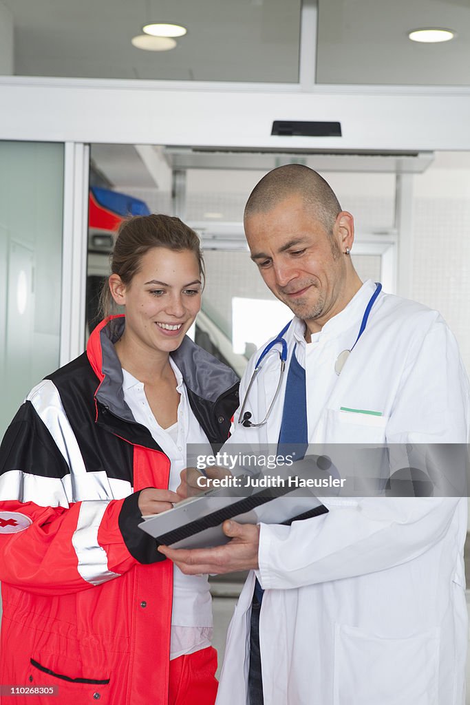 Paramedic and doctor examining file