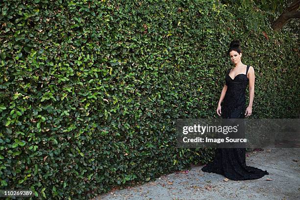 young woman wearing black evening dress, standing by hedge - studio city 個照片及圖片檔