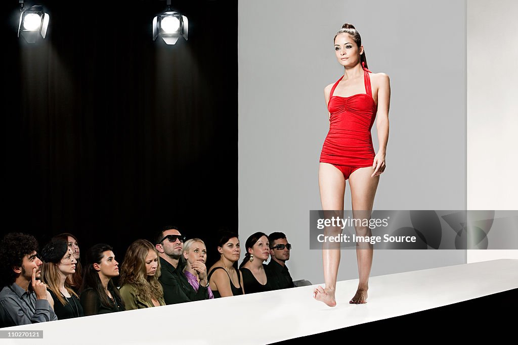 モデルレッドのスイムスーツを着てキャットウォークにファッションショー