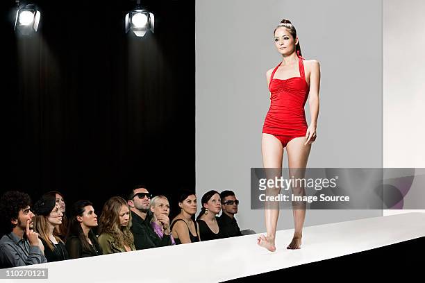 model wearing red swimsuit on catwalk at fashion show - fashion show stock pictures, royalty-free photos & images