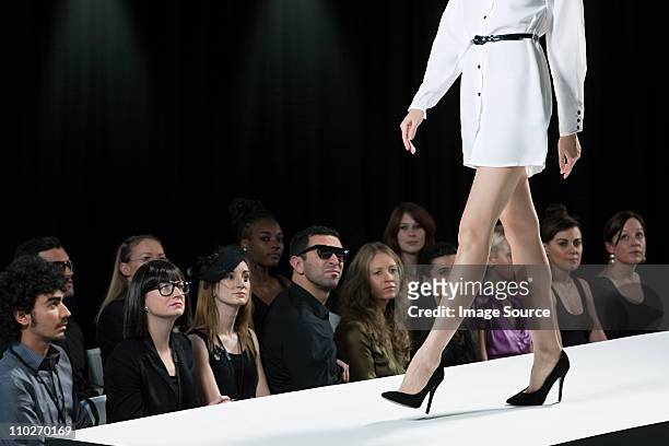 audience watching model on catwalk at fashion show, low section - modeshow stockfoto's en -beelden