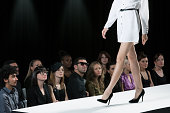 Audience watching model on catwalk at fashion show, low section