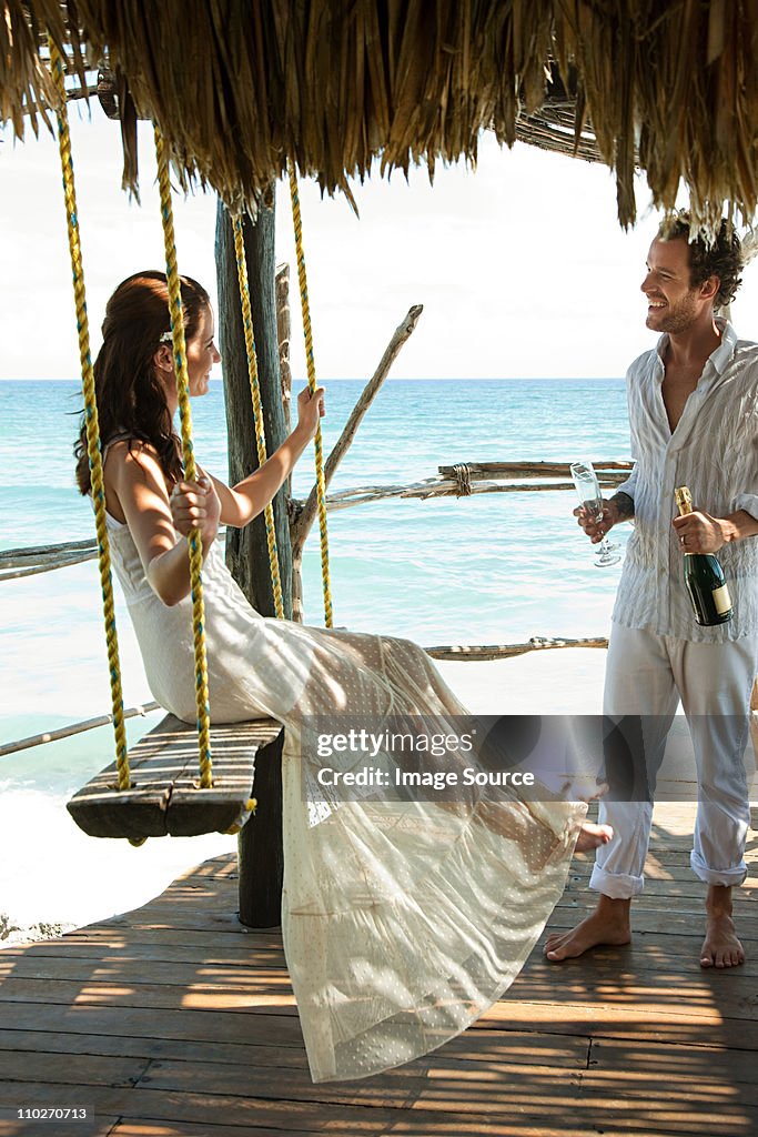 Mid adult couple with champagne, woman on swing