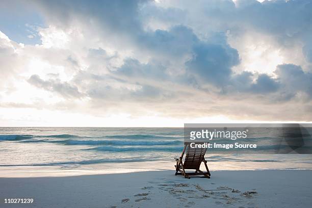 deck chair on sandy beach at water's edge - tranquil scene stock pictures, royalty-free photos & images