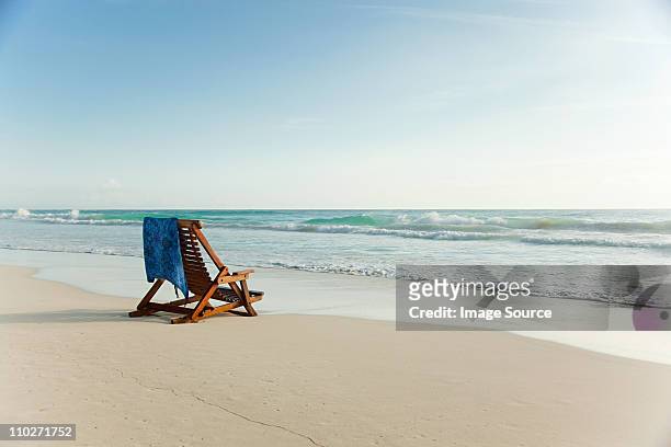 deck chair on sandy beach at water's edge - beach stock pictures, royalty-free photos & images