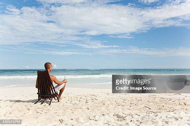 hombre sentado en la silla reclinable en la playa de arena - man on the beach relaxing in deckchair fotografías e imágenes de stock