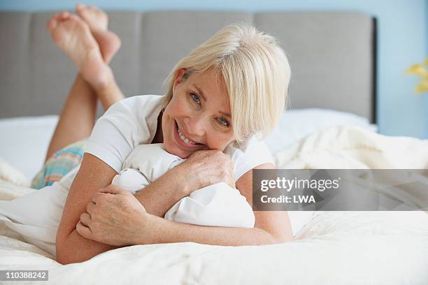 smiling senior woman, lying on bed - bettwäsche stock-fotos und bilder