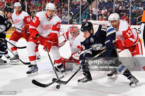 Jonathan Ericsson and Pavel Datsyuk, both of the Detroit Red Wings, work to knock the puck away from Derek Dorsett of the Columbus Blue Jackets...