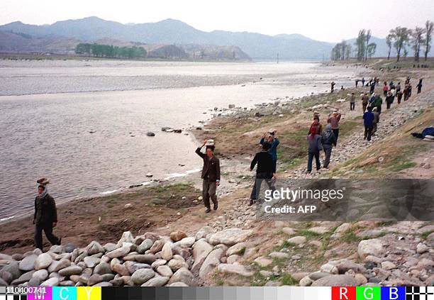 North Koreans carry rocks on their heads as they repair a riverbank 24 April in the wake of flooding which has destroyed thousands of acres of crops...