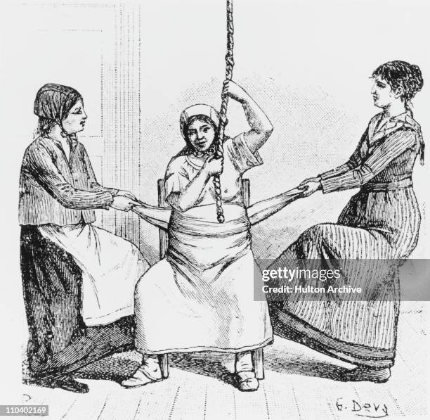 Woman being helped to give birth, on a birth chair, by two midwives, each pulling on a cloth wrapped around the mother's belly, California, USA,...