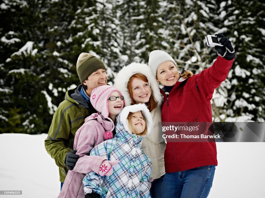 Mother taking self portrait of family in the snow