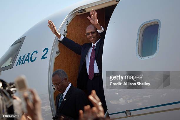 Former Haitian President Jean-Bertrand Aristide waves to the crowd upon disembarking a private plane at the airport March 18, 2011 in Port-au-Prince,...