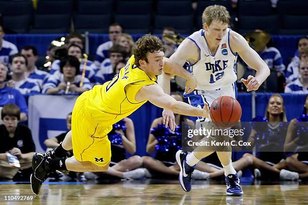 Zack Novak of the Michigan Wolverines dives for the ball alongside Kyle Singler of the Duke Blue Devils in the first half during the third round of...