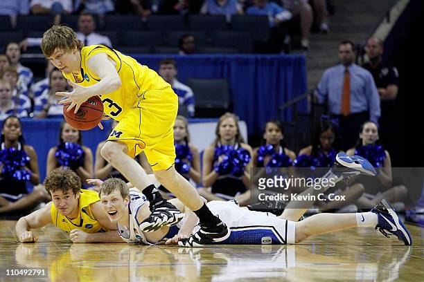 Matt Vogrich of the Michigan Wolverines picks up a loose ball in front of teammate Zack Novak and Kyle Singler of the Duke Blue Devils in the first...
