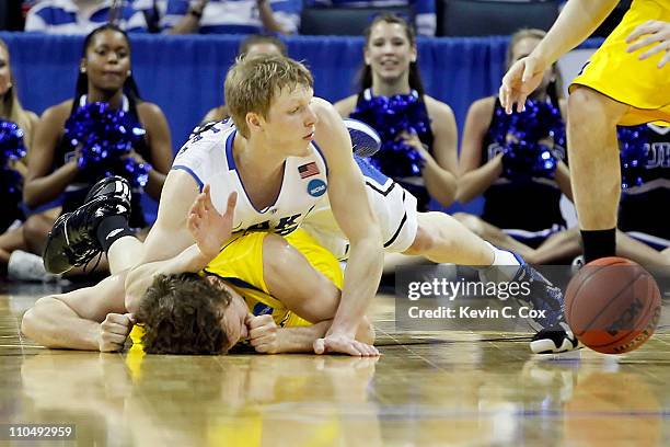 Zack Novak of the Michigan Wolverines is landed on after being jumped on by Kyle Singler of the Duke Blue Devils in the first half as they go for a...