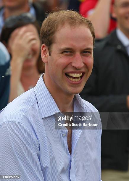 Prince William smiles after kicking an AFL ball towards photographers while attending a community BBQ on March 21, 2011 in Murrabit, Australia. His...