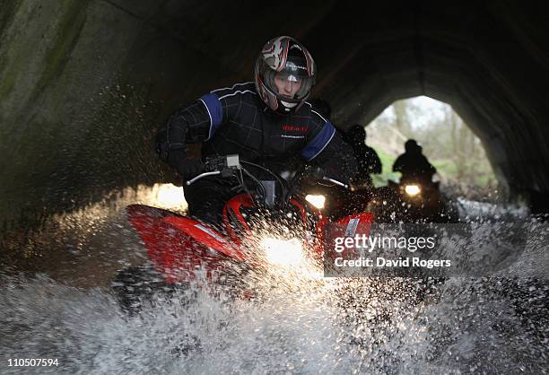 Chris Ashton, the Northampton Saints and England wing crashes through the watersplash on a quad bike during the Northampton Saints media day on March...