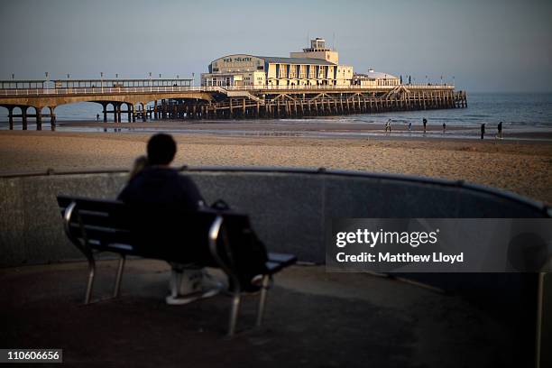 Couple sit on the beach in front of Bournemouth Pier at sunset on March 21, 2011 in Bournemouth, England. Located on the South Coast, the traditional...