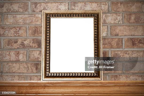 empty gold photo frame on mantelshelf & brick wall - photo frame on mantle piece stockfoto's en -beelden