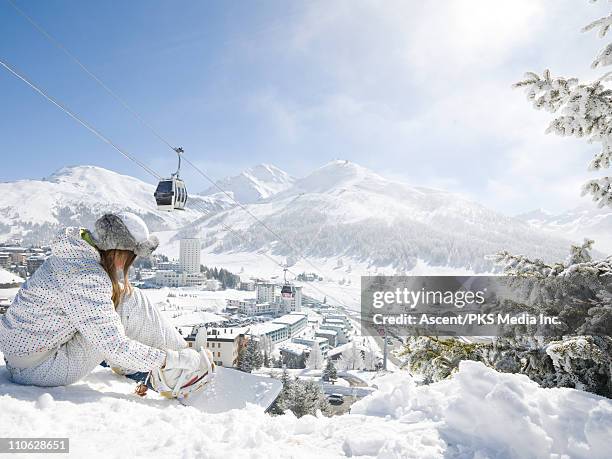 teenage girl tightens snowboard straps, tram above - sestriere stockfoto's en -beelden