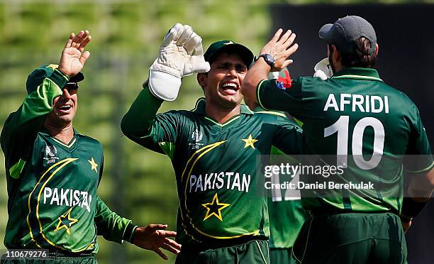 Shahid Afridi of Pakistan celebrates with team mates Kamran Akmal and Saeed Ajmal after taking the catch to dismiss Chris Gayle of West Indies off...