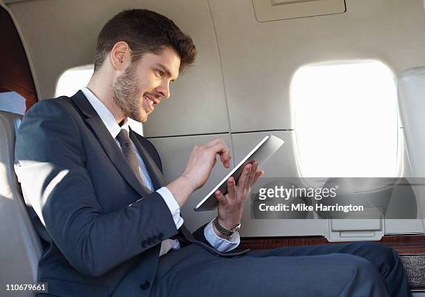 young business man using graphics tablet on plane - business jet stock-fotos und bilder