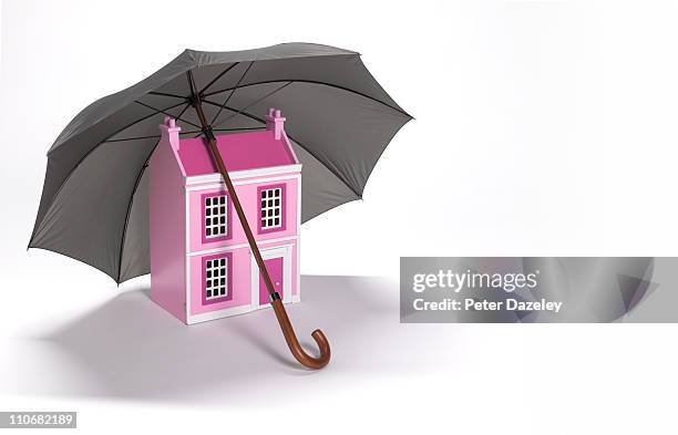 house sheltered by umbrella with copy space - home insurance stock pictures, royalty-free photos & images