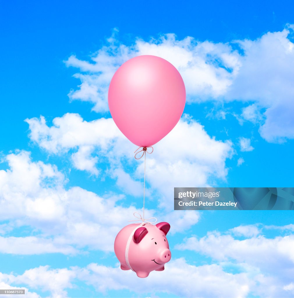 Piggy bank and balloon against sky