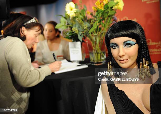 Woman signs a condolence book beside a wax figure of Elizabeth Taylor in one of her most famous roles, Cleopatra, at Madame Tussauds in Hollywood,...