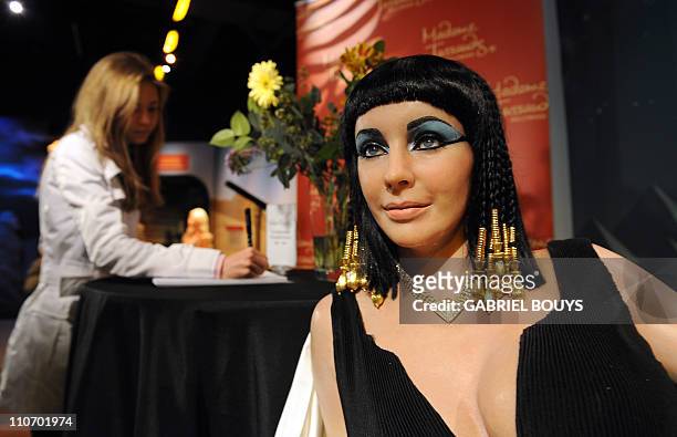 Woman signs a condolence book beside a wax figure of Elizabeth Taylor in one of her most famous roles, Cleopatra, at Madame Tussauds in Hollywood,...
