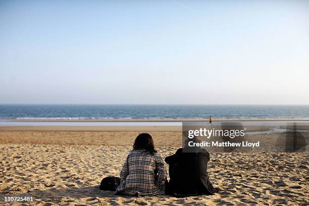 Couple sit on the beach in front of Bournemouth Pier at sunset on March 21, 2011 in Bournemouth, England. Located on the South Coast, the traditional...