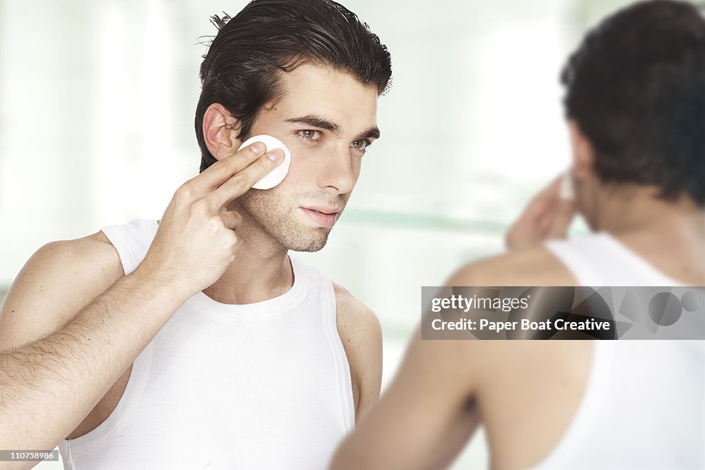 Man looking at his reflection; using facial toner