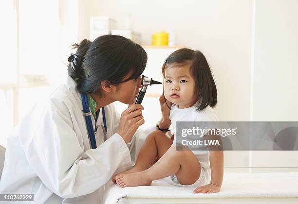 doctor examining girl's ear, with otoscope - ent photos et images de collection