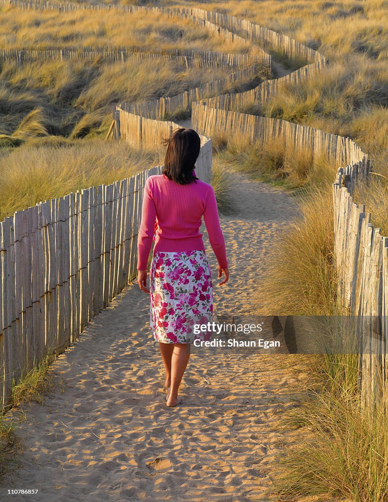 Woman walking on sand towards beach