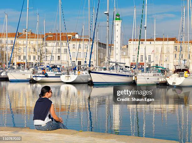 woman sitting by harbour at la rochelle - la rochelle 個照片及圖片檔