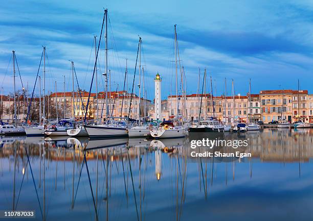 lighthouse reflected in harbour at dusk - la rochelle stock pictures, royalty-free photos & images