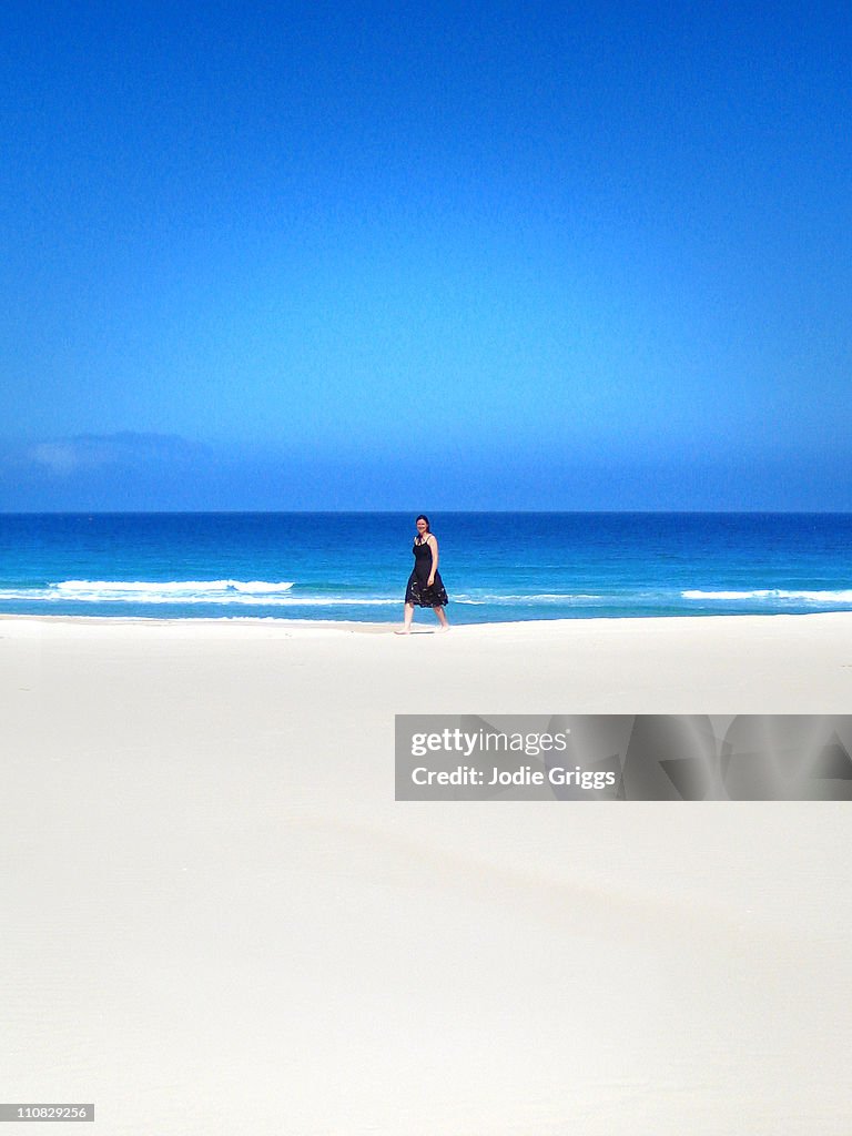 Woman walking across sand dunes