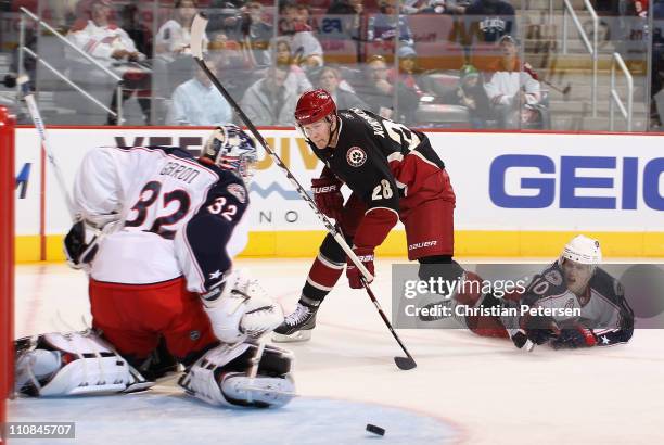 Lauri Korpikoski of the Phoenix Coyotes shoots the puck wide of goaltender Mathieu Garon and Kris Russell of the Columbus Blue Jackets during the...