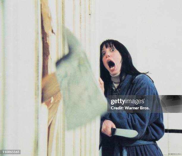 Wendy Torrance, played by American actress Shelley Duvall, recoils in shock as her husband chops through the bathroom door with a fire axe in a scene...