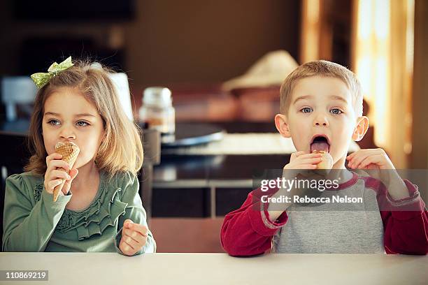 happy boy and girl eating ice cream cones - boy and girl eating ice cream stock-fotos und bilder