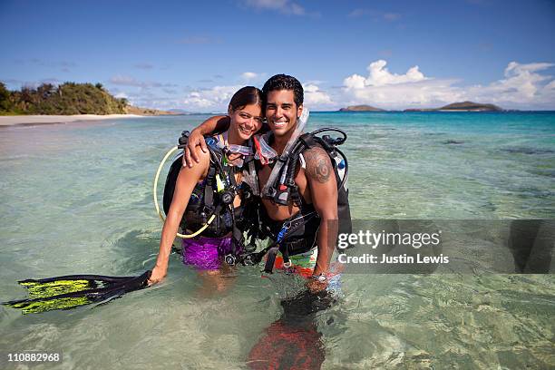 couple in dive gear hugging in water. - couple portrait stock pictures, royalty-free photos & images