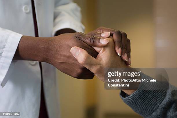 doctor holding patient's hand - handshake closeup stock-fotos und bilder