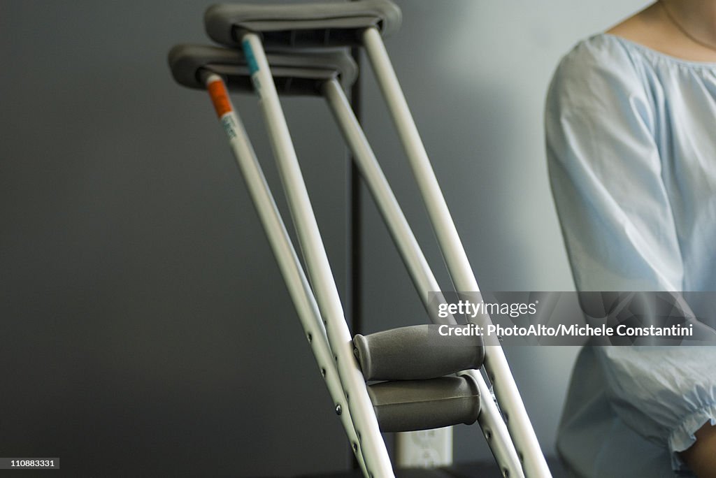 Pair of crutches resting beside seated patient