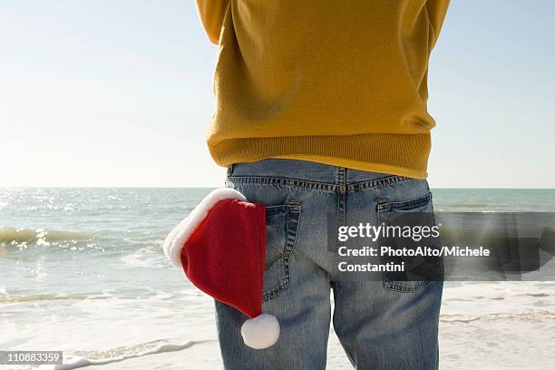 man standing on beach looking at view, santa hat in back pocket - bolso traseiro imagens e fotografias de stock