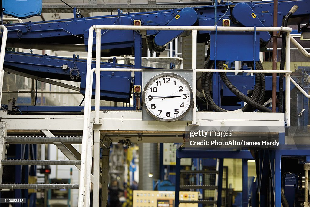 Clock mounted beside metal stairs in carpet tile factory