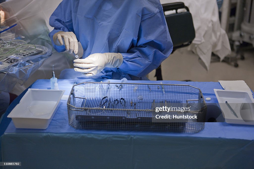 Surgical technologist drawing solution into syringe for cataract surgery