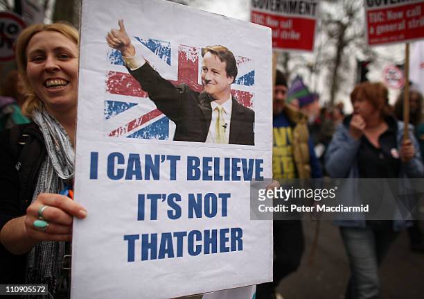 Woman holds a placard depicting British Prime Minister David Cameron as she marches in protest at government cuts on March 26, 2011 in London,...